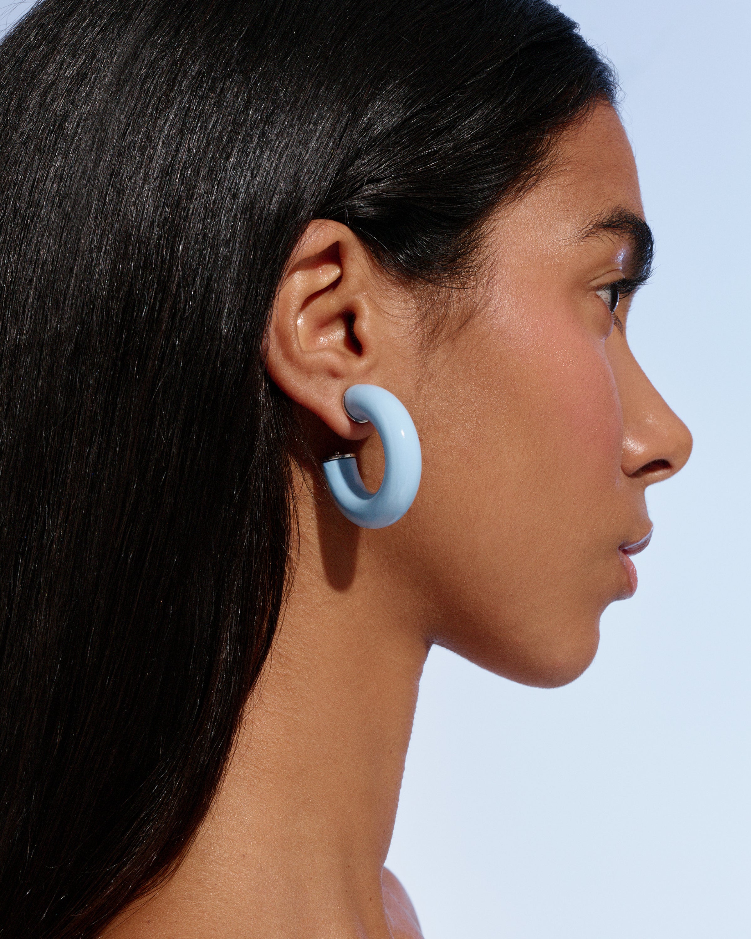 close-up side profile of a model wearing pale blue Alba Hoops against a soft blue background