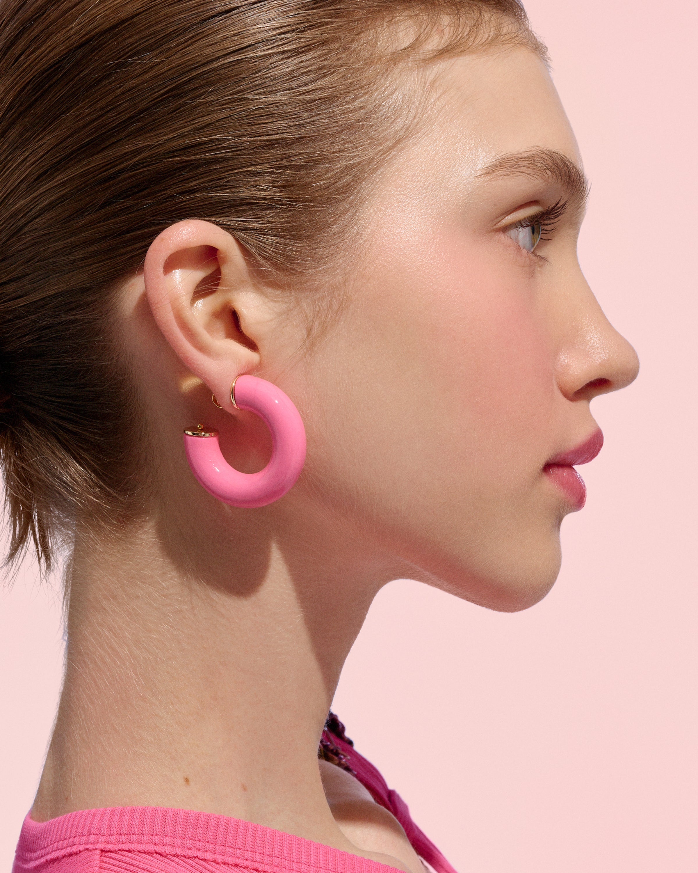 close-up side profile of a model wearing bright pink Alba Hoops against a soft pink background