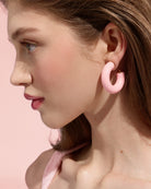 Close-up of a model wearing pale pink Alba Hoops against a pink background