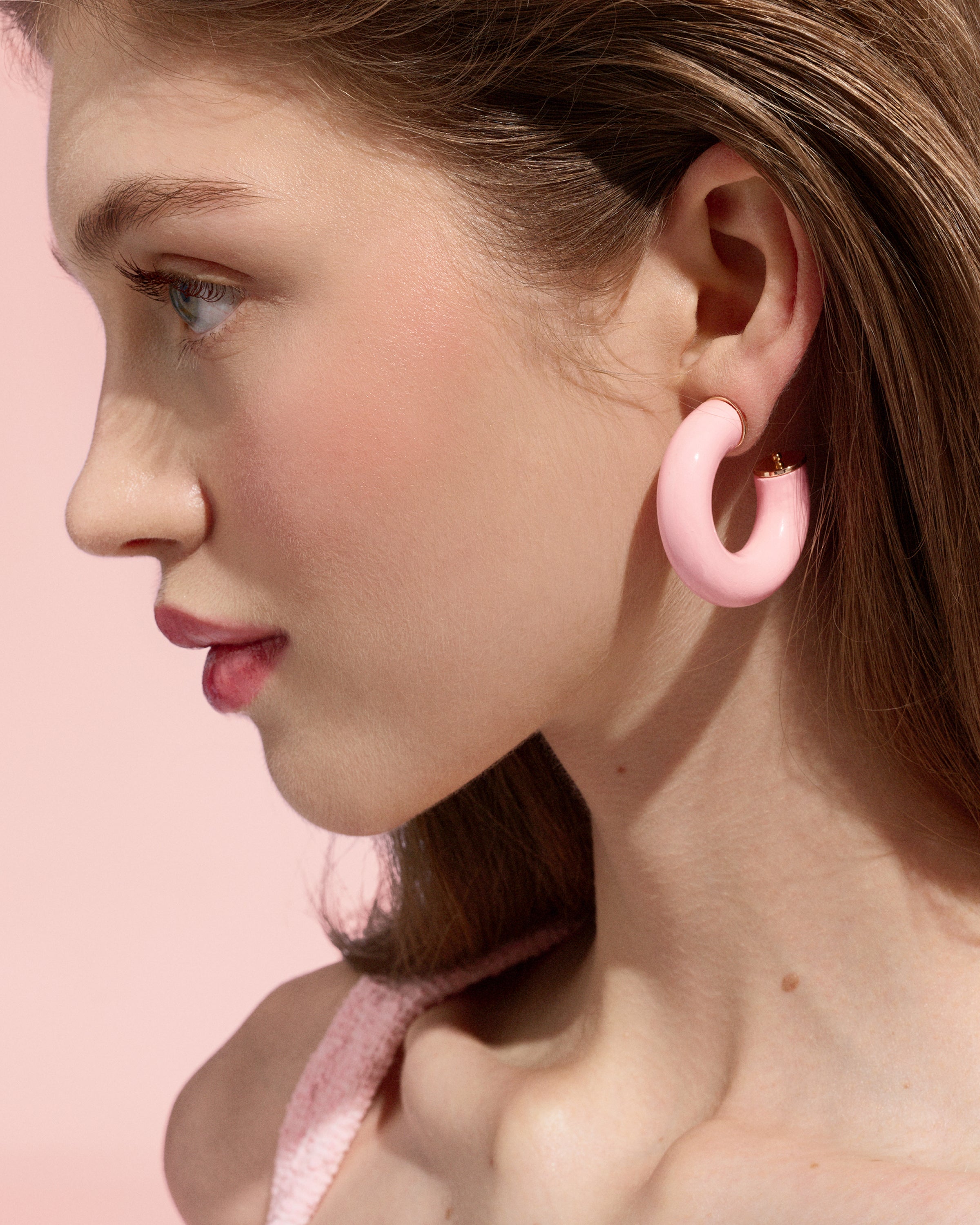 Close-up of a model wearing pale pink Alba Hoops against a pink background