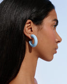close-up side profile of a model wearing pale blue Alba Hoops against a soft blue background